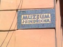 Nápisová deska na nároží muzea vytvořená společně s pomníkem.