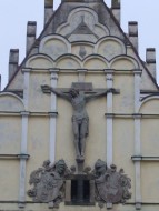 Výzdoba průčelí kostela sv. Bartoloměje v Pardubicích- Ukřižovaný, erby, boží oko, žehnající boží ruka